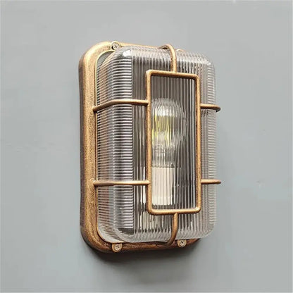 Vintage brass gas station canopy wall light with textured frame ribbed glass and exposed bulb behind metal bars