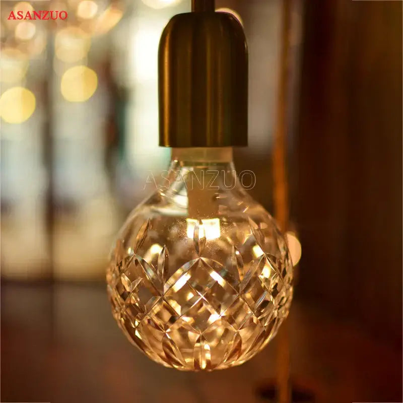 A vintage brass pendant lamp with a warm glowing faceted glass bulb for dining room use