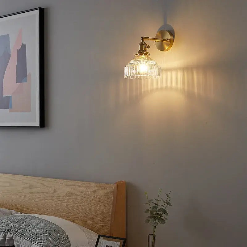 Vintage brass wall lamp with ribbed glass pull chain shade casting warm light for living room use