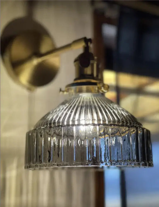 Vintage brass wall sconce with clear ribbed glass shade designed as a bedroom wall lamp