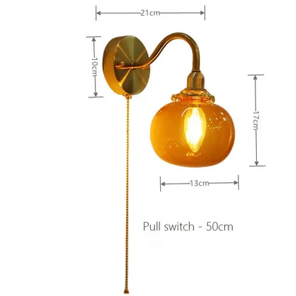 Vintage brass wall sconce lamp with rounded amber ribbed glass shade and pull chain switch for bedroom use