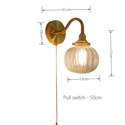Vintage brass wall sconce lamp with gold-toned curved arm and ribbed translucent glass globe for bedroom use