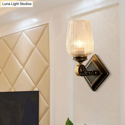 Vintage brass living room sconce featuring an antique brass finish and a clear textured glass shade