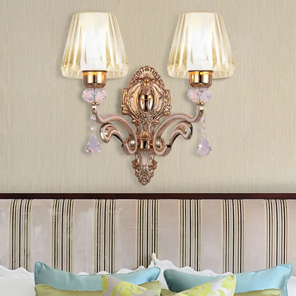 Ornate rose gold wall lamp with clear glass shade featuring two cream fluted shades and lavender crystal droplets