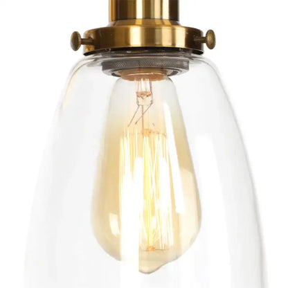 Vintage brass wall light fixture with warm-toned edison bulb encased in clear glass dome for bedroom use