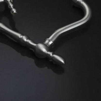 Vintage brushed nickel kitchen faucet with swivel spout and decorative silver-toned necklace chain featuring ornate design