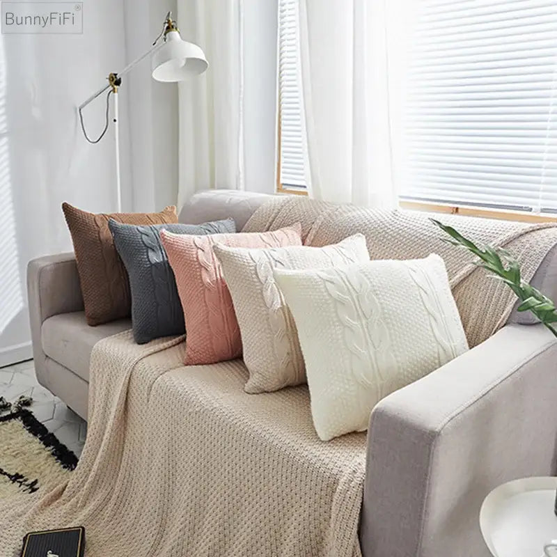 A cozy cream-colored decorbites cable knit throw blanket with textured cable knit double pattern draped over sofa