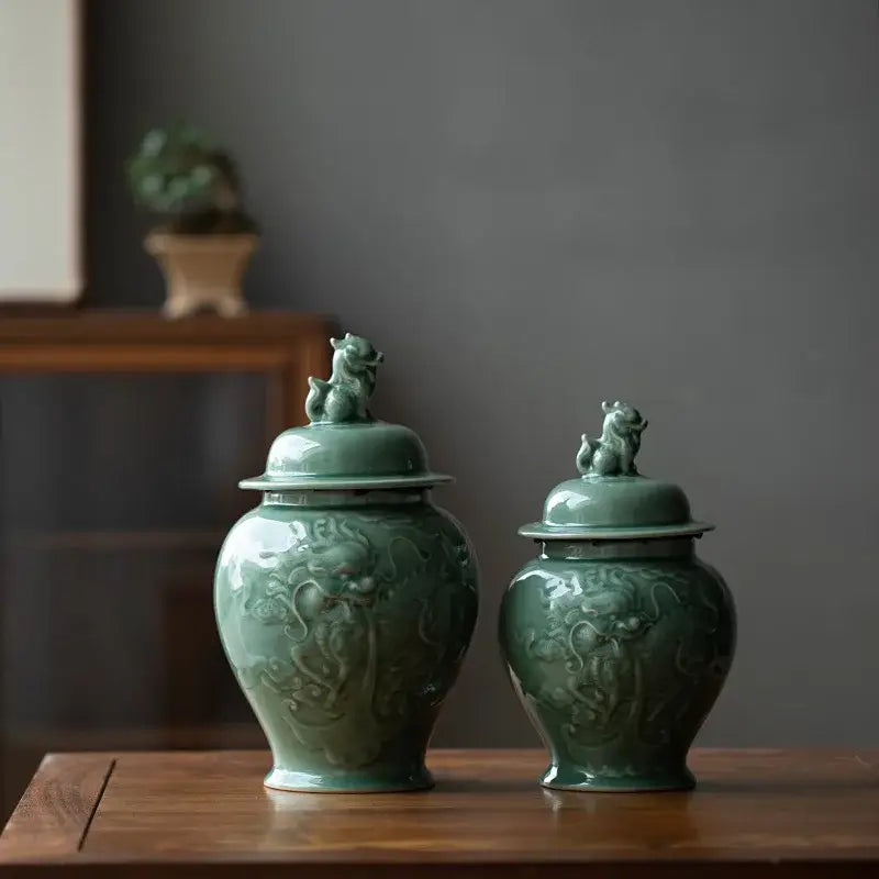 Two jade-green ceramic tea caddies with intricate dragon relief and lion figurine lids for kitchen storage jars