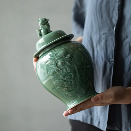 A vintage celadon green ceramic tea caddy with intricate dragon relief carvings and matching lid storage jar