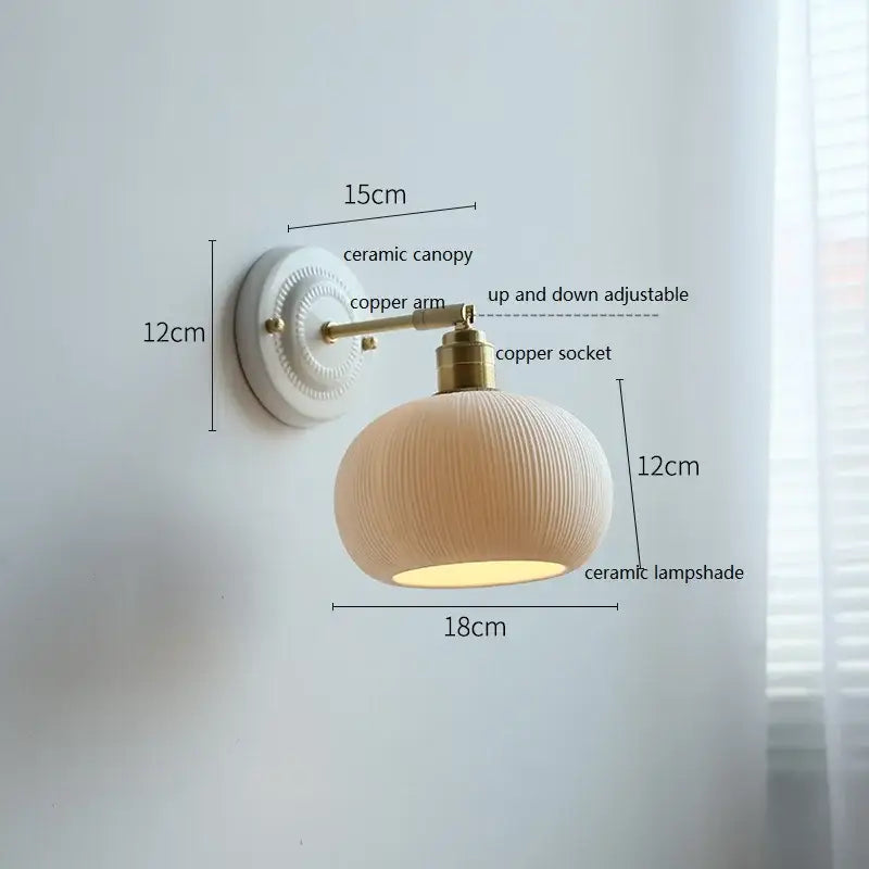 Cream-colored decorbites ceramic wall lamp with ribbed ceramic shade and brass-finished copper arm for bedroom decor