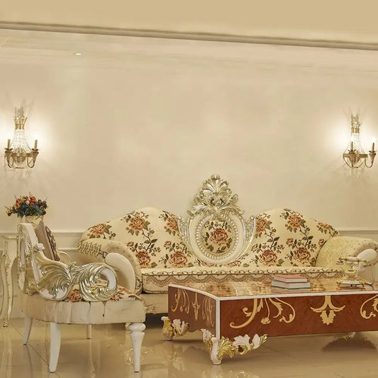 Cream-colored floral sofa with ornate silver-gold detailing complements vintage champagne finish wall light with clear crystal