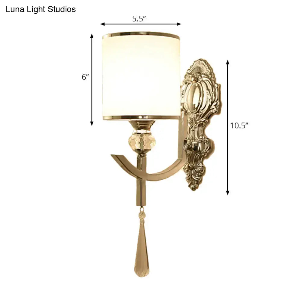 Gold-toned vintage wall sconce with carved backplate, off-white cylindrical lampshade, and crystal accents for corridor lighting