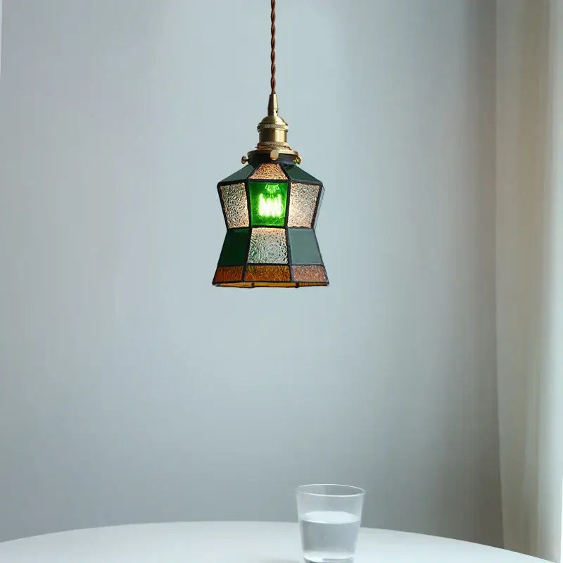 A vintage colorful glass tiffany pendant lamp with brass fixture featuring green dark teal and amber stained glass panels