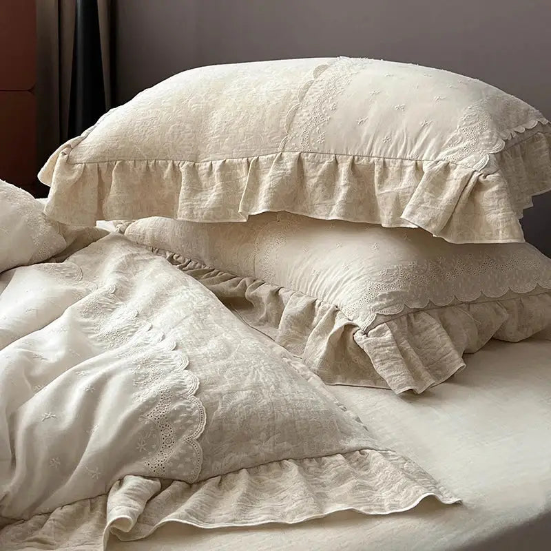 Cream-colored linen pillowcases with soft textured fabric and jacquard lace ruffles in a vintage bedding set