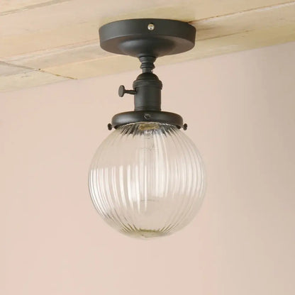 Vintage dark bronze semi flush mount ceiling light with black metal fixture and clear ribbed glass globe for bedroom