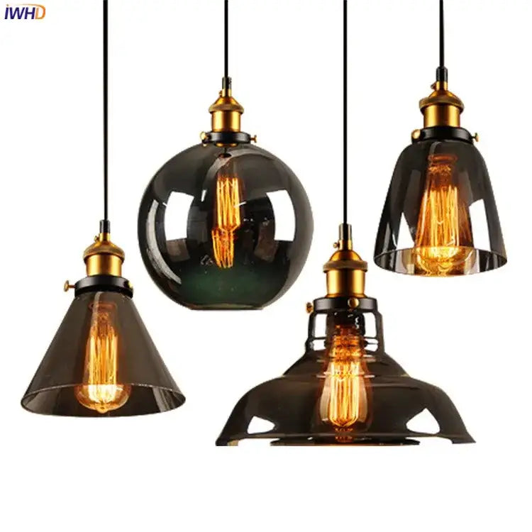 Set of four vintage dark glass pendant lights with brass accents and exposed filament bulbs for dining room use