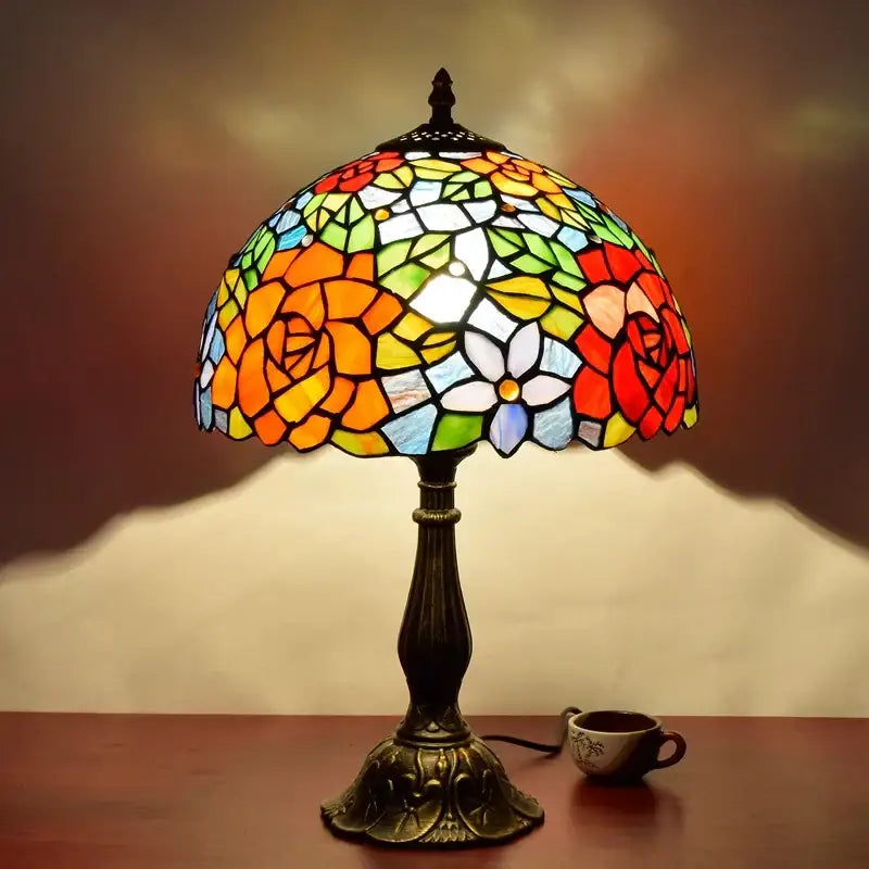 Vintage dragonfly tiffany stained glass table lamp with vibrant floral design in red orange yellow green and blue hues on bronze base