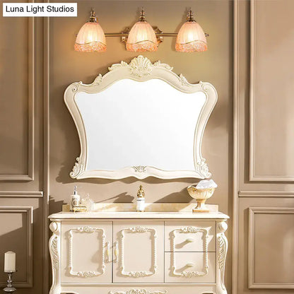 Antique white ornate bathroom vanity with carved details and matching mirror complementing vintage amber glass sconces