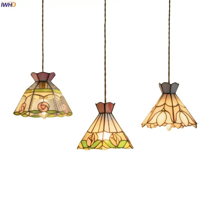Three elegant tiffany-style pendant lights with colorful flower stained glass shades in warm amber green and rose hues for decorbites