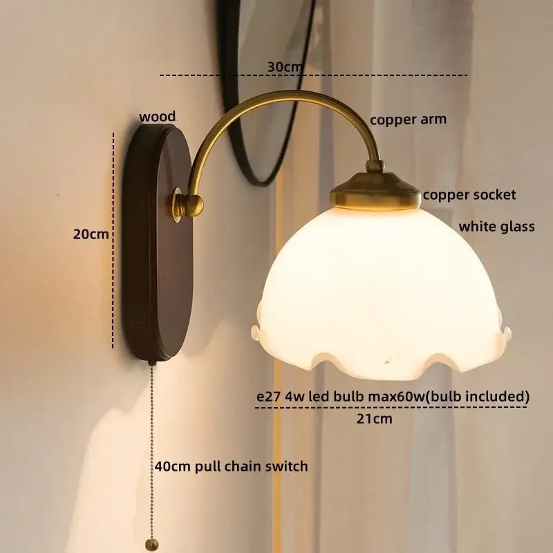 Antique brass-finished wall lights with scalloped white glass copper led shade and dark wood backplate for bedroom