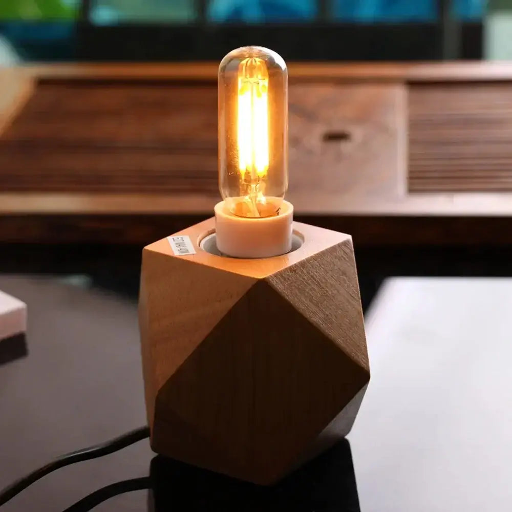 A warm glowing vintage gold tubular led bulb with clear glass on a geometric wooden base for dining room use