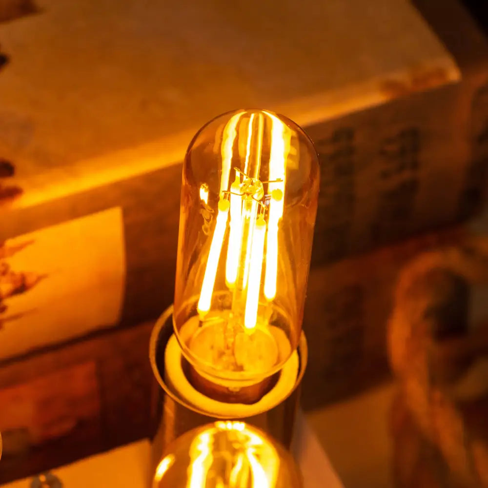 Warm-toned vintage gold candelabra tubular led bulb with clear glass and visible filament strands for dining room