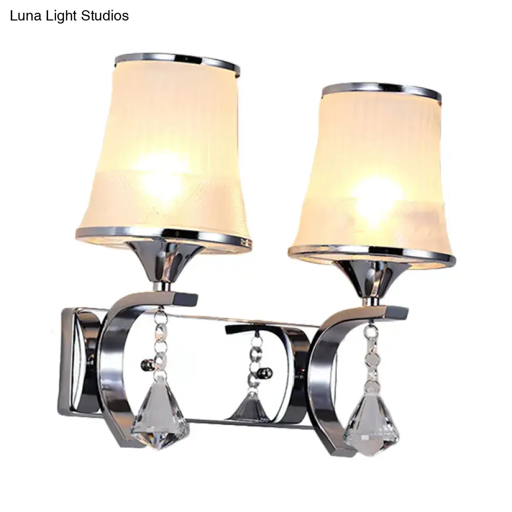 Chrome finished wall lamp with two warm cylindrical lampshades and clear glass crystal teardrop pendants for bedroom use