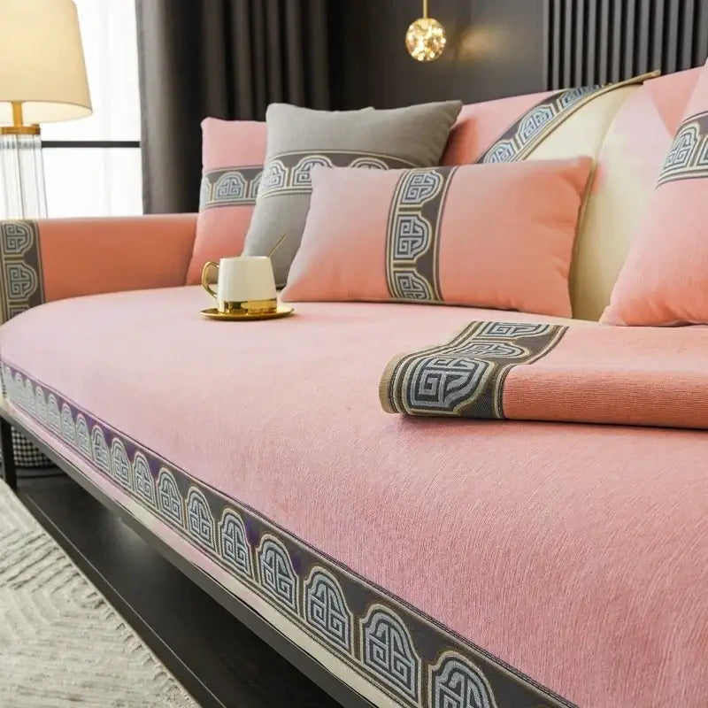 Pink sofa cushion with decorative dark gray and white geometric border made of soft textured fabric for living room use