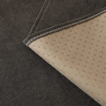 Dark gray textured fabric mat showing the beige dotted non-slip backing with white edge stitching for sofa cover use
