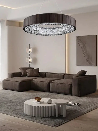 Dark brown sectional sofa with plush cushioned seating and modern angular design beneath gray glass large ceiling pendant light
