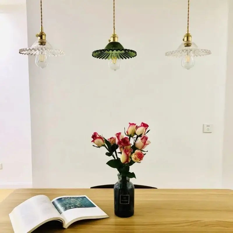 Three vintage-style pendant lights with green brass glass led scalloped shade hanging above a wooden kitchen table