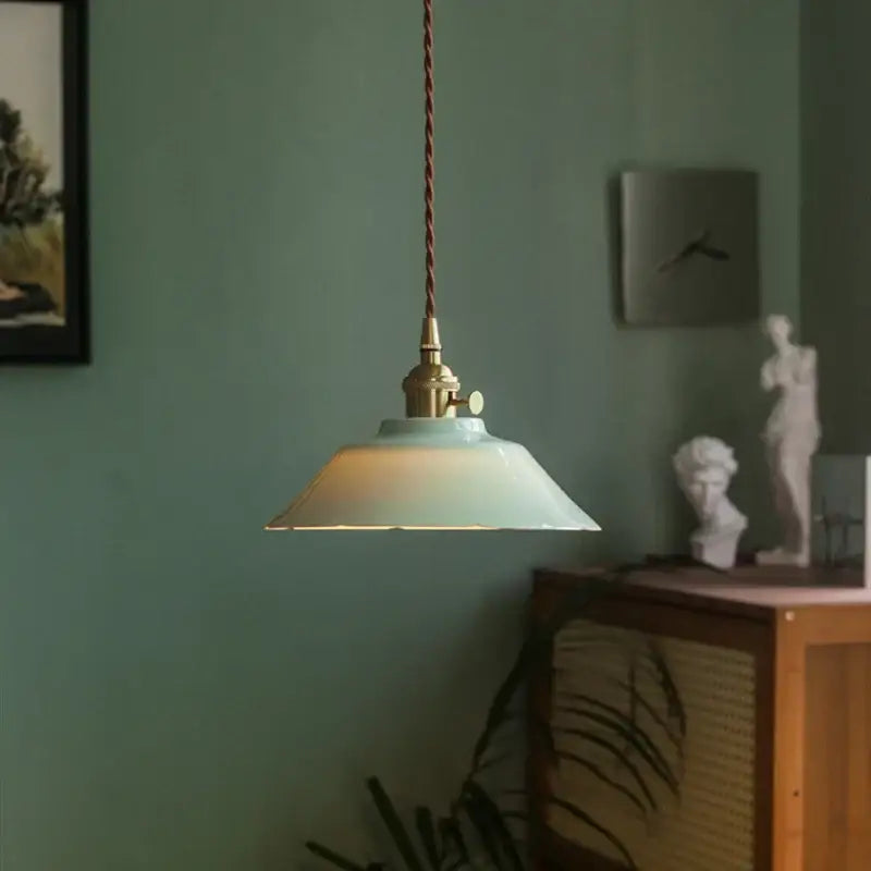 Vintage green ceramic pendant light with mint green ceramic shade and brass hardware hanging by twisted brown cord