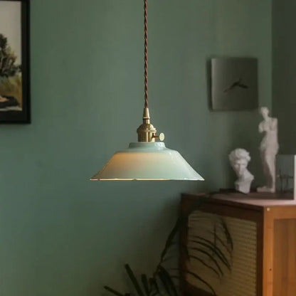Vintage green ceramic pendant light with mint green ceramic shade and brass hardware hanging by twisted brown cord