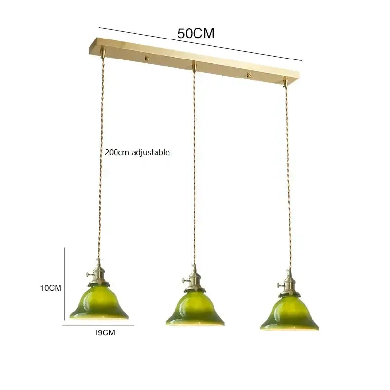 A set of three vintage green glass pendant lamps with brass hardware and adjustable chains for kitchen lighting