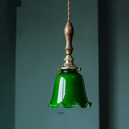 Vintage pendant lamp with glossy emerald green glass bell shade dark wood handle and brass hardware for kitchen use