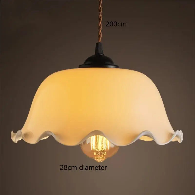 Warm cream-colored glass vintage pendant lamp with scalloped edge and black metal fixture for kitchen lighting