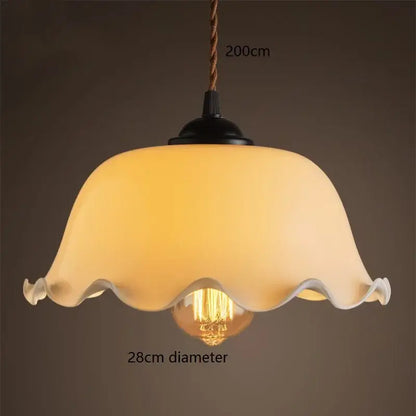 Warm cream-colored glass vintage pendant lamp with scalloped edge and black metal fixture for kitchen lighting