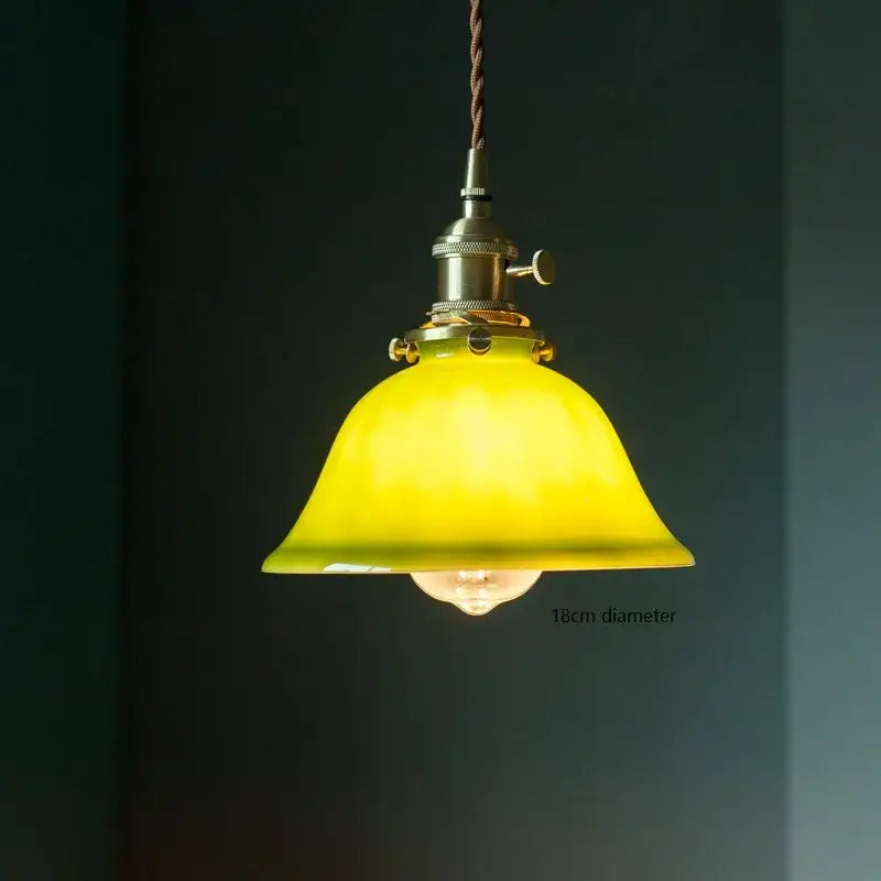 Vintage pendant lamp featuring a warm yellow glass shade with brass hardware and braided cord for kitchen lighting
