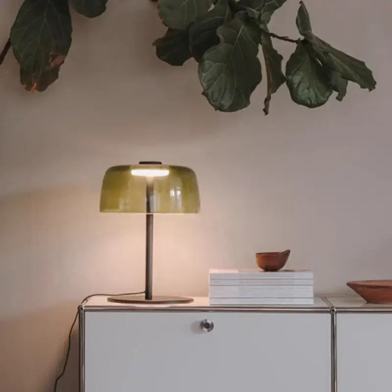 A sleek vintage green glass table lamp with a translucent olive-green shade and slender metallic base for luxury decor