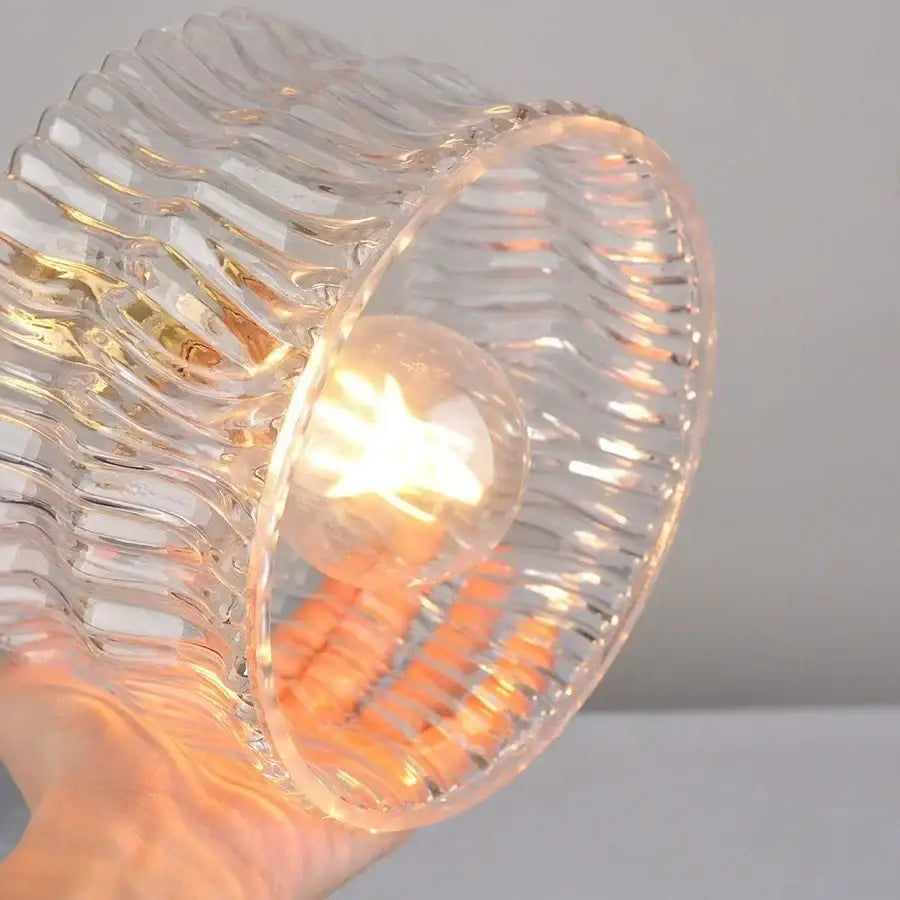 Clear glass wall light with wavy ribbed texture and warm bulb inside vintage green glass copper knob switch design