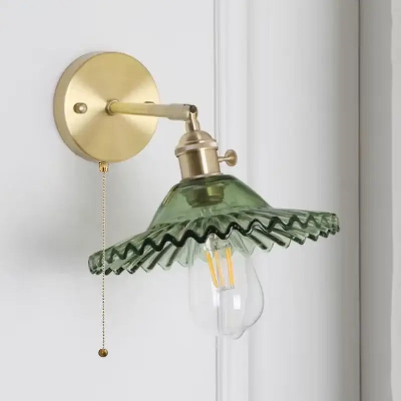 Vintage green glass wall light with brass base and pull chain switch featuring scalloped shade for bedroom sconce use