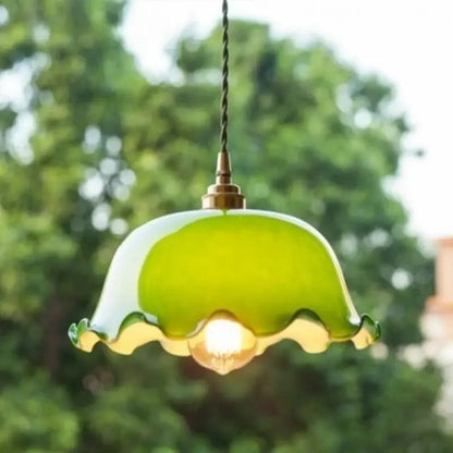 A delicate green lotus led pendant light with a ruffled glass shade and brass accents for dining room use