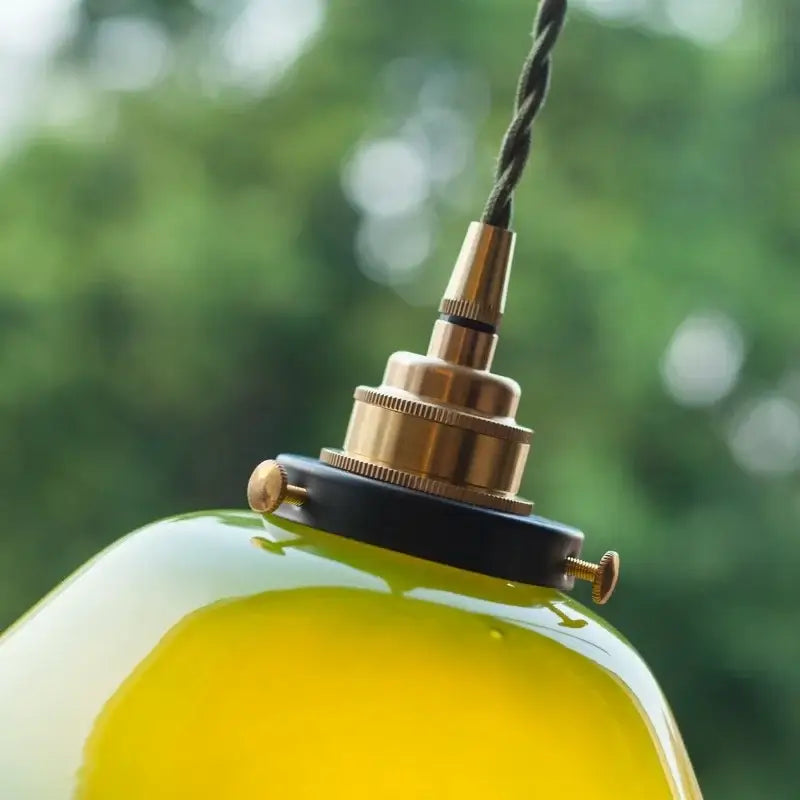 A vibrant yellow-green glass vintage green lotus led pendant light with brass fixture and black cord for dining room