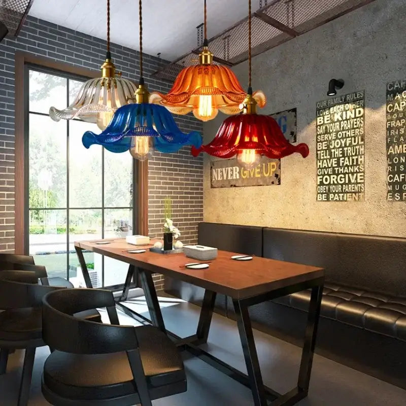 Vintage hand blown glass pendant lights with vibrant colors and brass accents hanging above wooden dining table