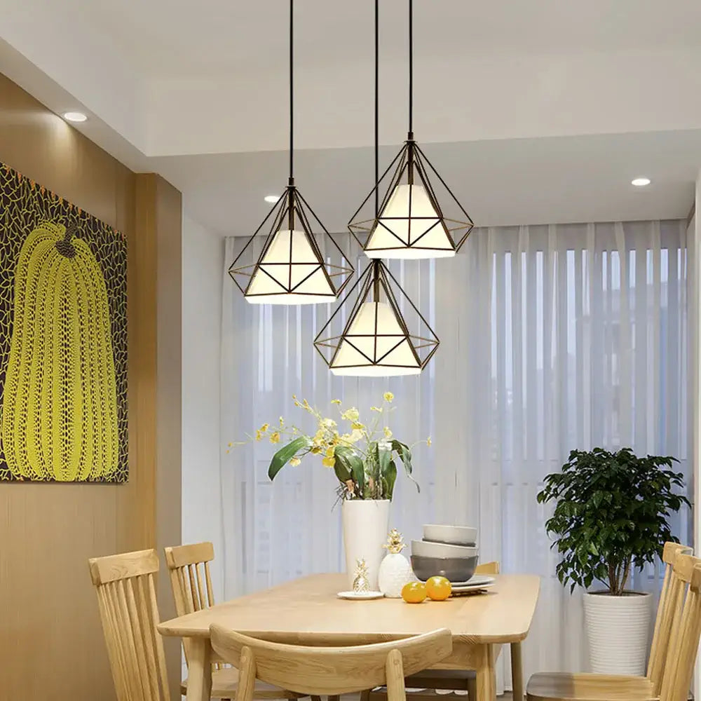 Three black metal cage pendant lights with white frosted glass shades hang above a wooden dining table decorbites black metal vintage industrial pendant light
