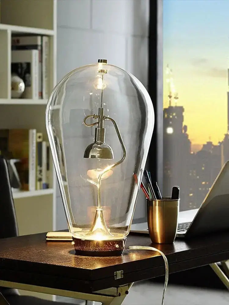A vintage industrial glass desk lamp with a transparent dome, brass base, and exposed filament bulb for decorbites glass desk use