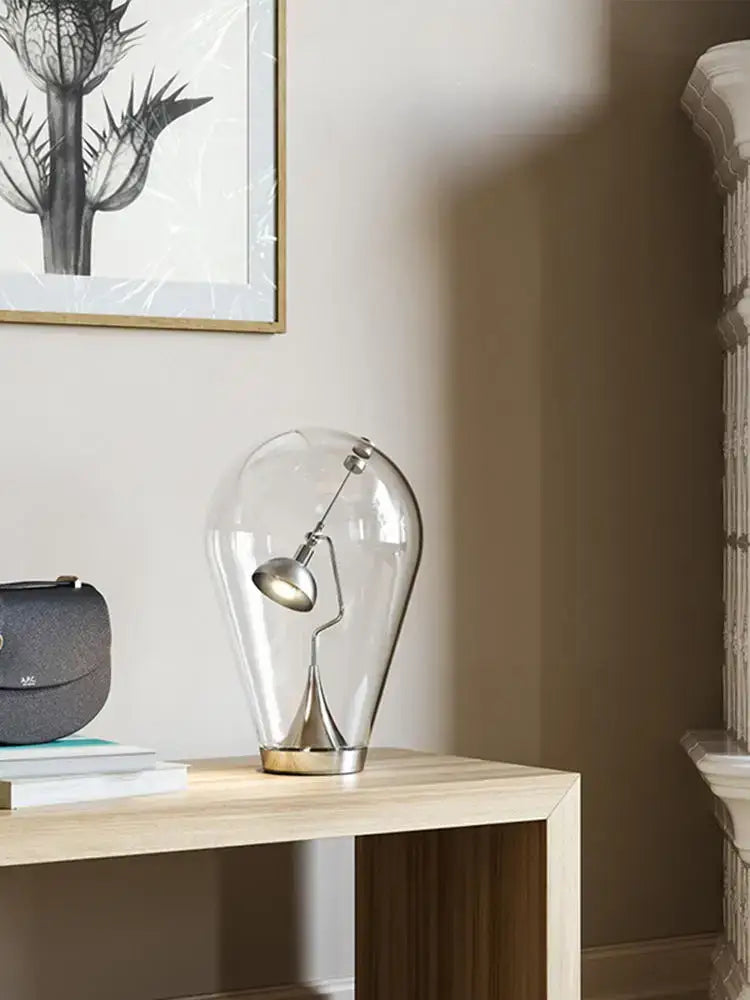 A sleek decorbites glass desk lamp with transparent glass, metallic silver base, and articulated arm for bedroom decor