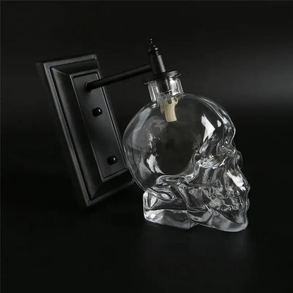 Vintage industrial glass skull wall sconce with clear glass skull bottle, black metal fixture, and white cork stopper