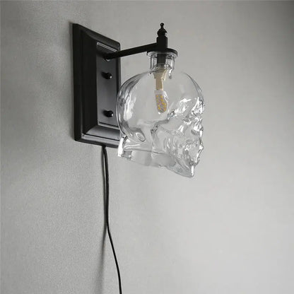 Clear glass skull wall sconce with black metal bracket and arm for vintage industrial living room lighting