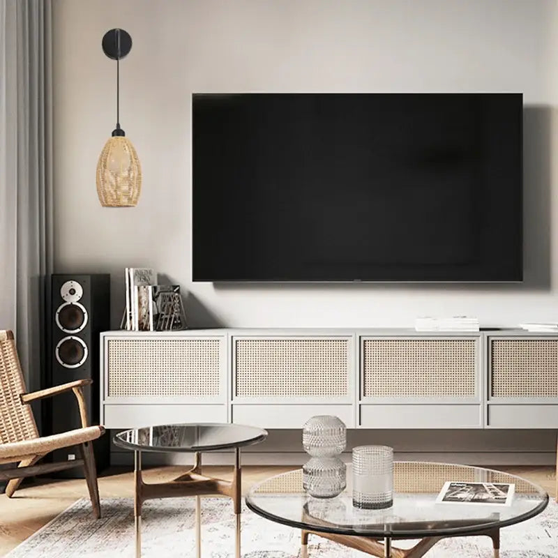 Black flat-screen television mounted above a white cane-backed media console featuring wall lamp decorbites industrial hemp